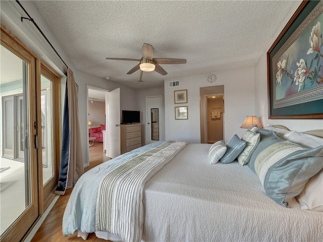 bedroom featuring light wood-type flooring, a textured ceiling, and ceiling fan