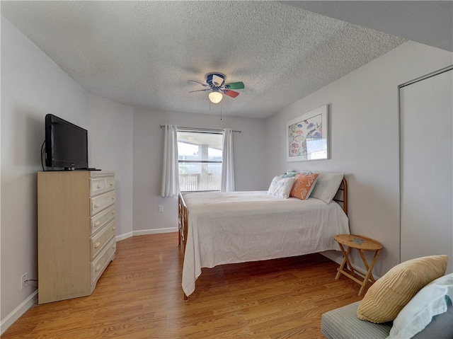 bedroom with light wood-type flooring, a textured ceiling, and ceiling fan