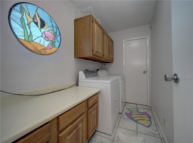 clothes washing area featuring a textured ceiling, light tile patterned floors, cabinets, and washing machine and clothes dryer