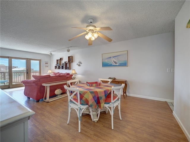 dining room with a textured ceiling, hardwood / wood-style flooring, and ceiling fan