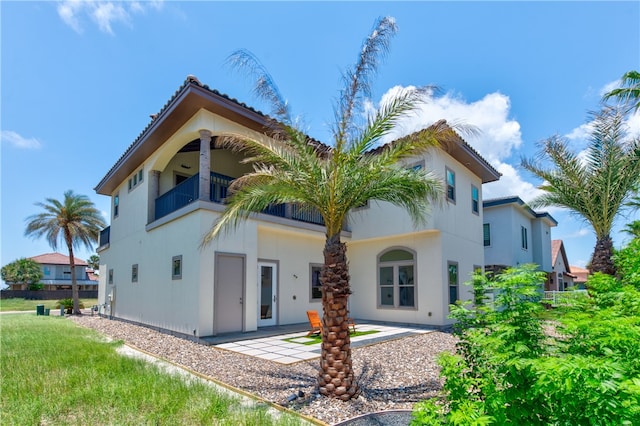 back of property with a balcony, a yard, and a patio area