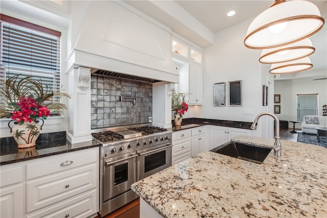 kitchen with light stone countertops, decorative light fixtures, double oven range, and white cabinets