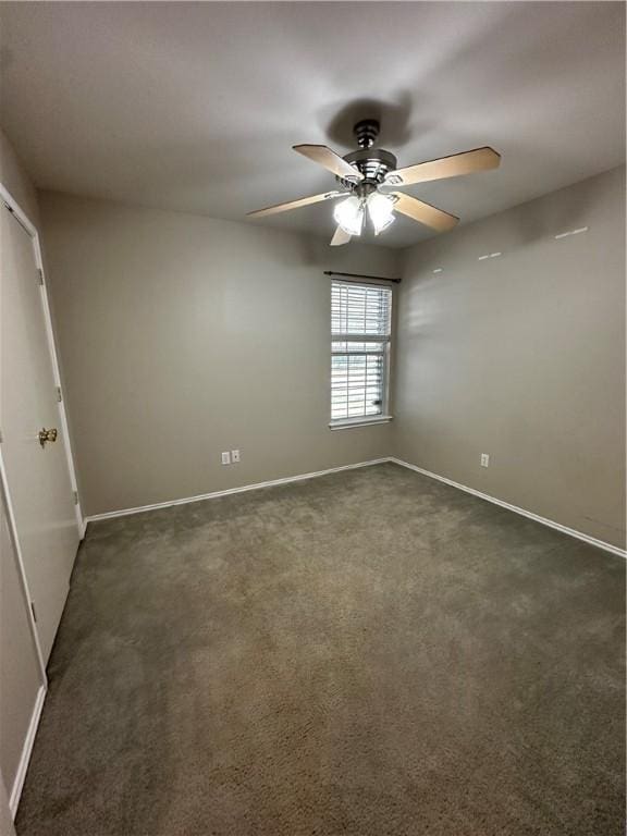 unfurnished room with dark colored carpet, baseboards, and a ceiling fan