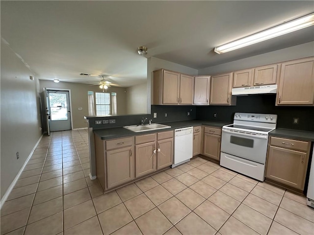 kitchen with under cabinet range hood, white appliances, dark countertops, and a sink