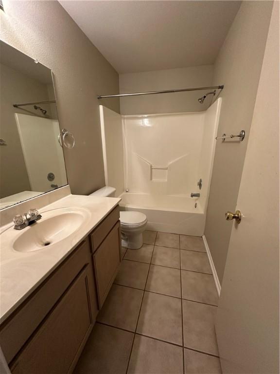 bathroom with bathing tub / shower combination, toilet, vanity, and tile patterned flooring