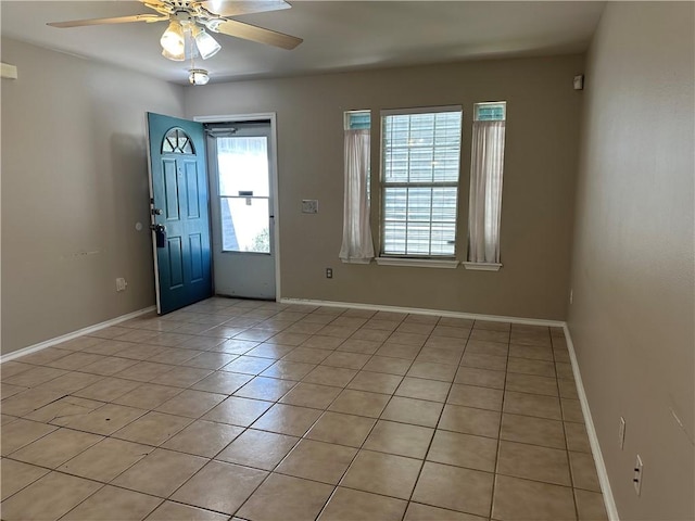 foyer entrance with light tile patterned floors, a ceiling fan, and baseboards