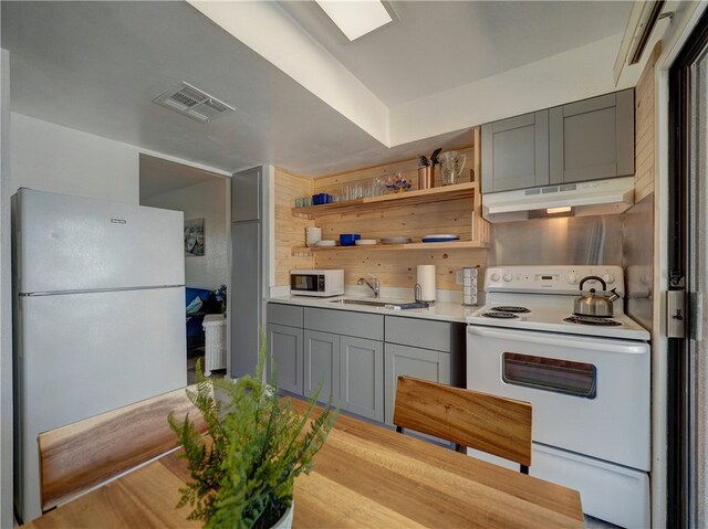 kitchen with gray cabinets, white appliances, and sink