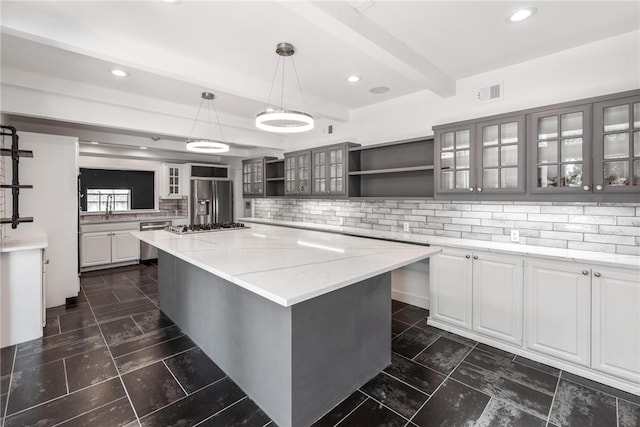 kitchen with stainless steel appliances, a center island, hanging light fixtures, tasteful backsplash, and light stone countertops