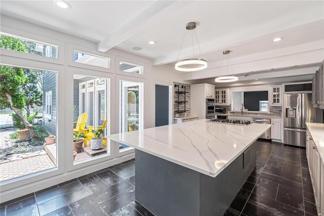 kitchen with white cabinets, stainless steel appliances, a center island, and decorative light fixtures