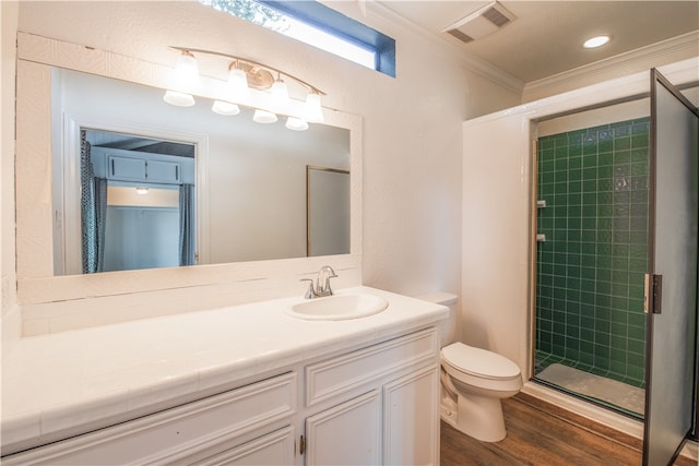 bathroom featuring wood-type flooring, a shower with door, crown molding, vanity, and toilet