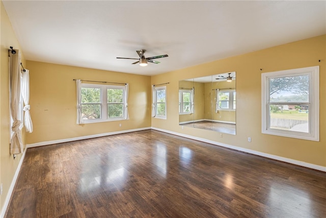 empty room featuring a wealth of natural light, dark wood-type flooring, and ceiling fan