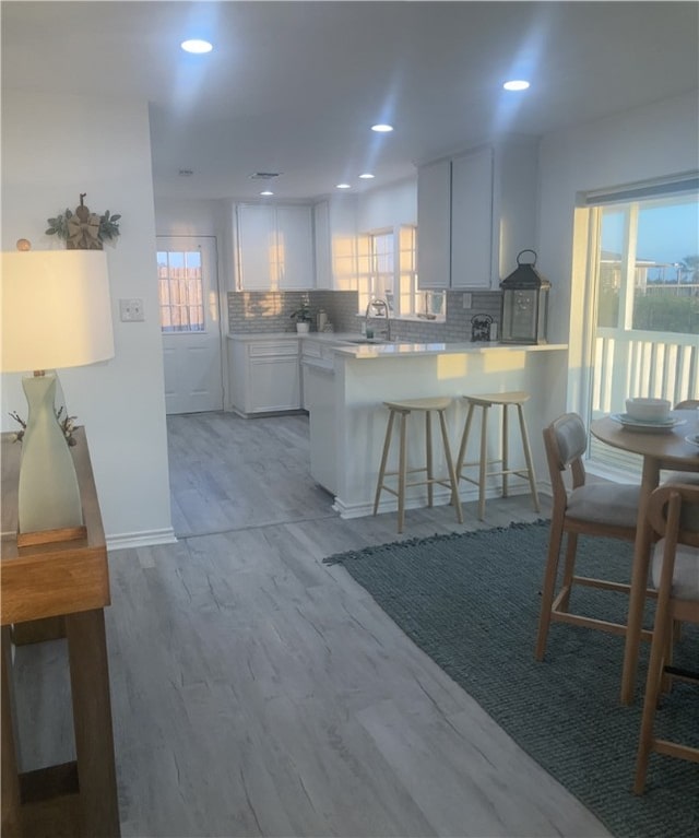kitchen with plenty of natural light, decorative backsplash, a peninsula, a sink, and recessed lighting