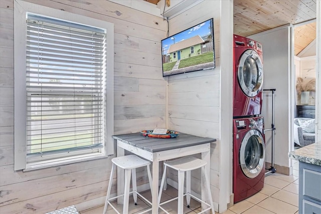 washroom with wooden ceiling, stacked washer / dryer, light tile patterned floors, and wood walls