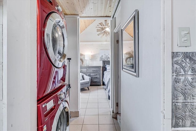 laundry area featuring stacked washer / dryer, wood ceiling, and light tile patterned floors