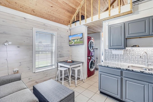 kitchen with wood ceiling, sink, stacked washer and clothes dryer, vaulted ceiling, and light tile patterned floors