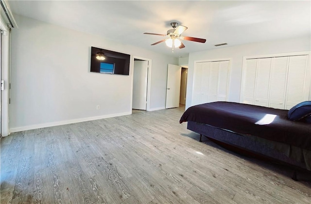 bedroom with ceiling fan, two closets, and light wood-type flooring