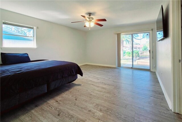 bedroom featuring hardwood / wood-style flooring, ceiling fan, access to outside, and multiple windows