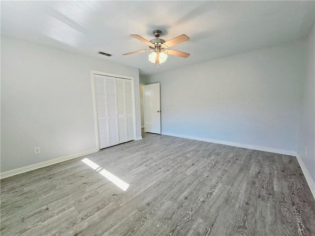 unfurnished bedroom featuring hardwood / wood-style flooring, ceiling fan, and a closet