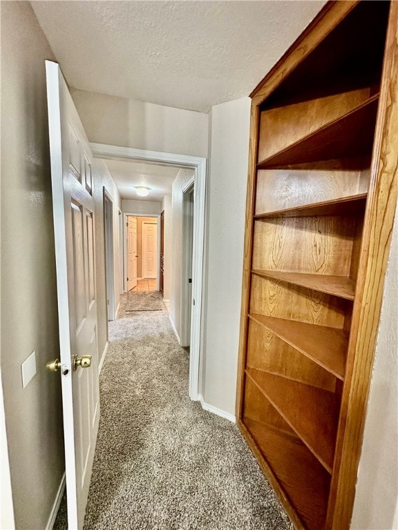 hallway featuring light colored carpet and a textured ceiling