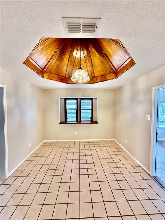 spare room featuring a textured ceiling, a healthy amount of sunlight, and light tile patterned flooring