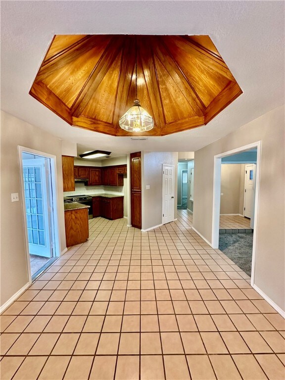 kitchen featuring black / electric stove, light tile patterned floors, and a raised ceiling