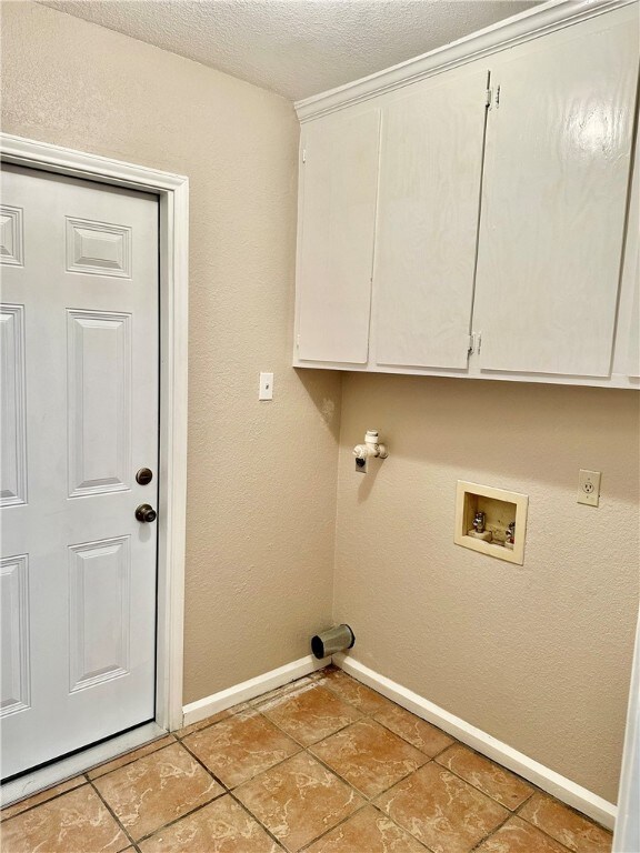 clothes washing area with a textured ceiling, hookup for a washing machine, and cabinets