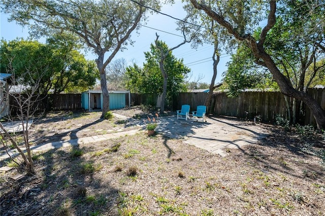 view of yard with an outbuilding, a patio area, a storage unit, and a fenced backyard