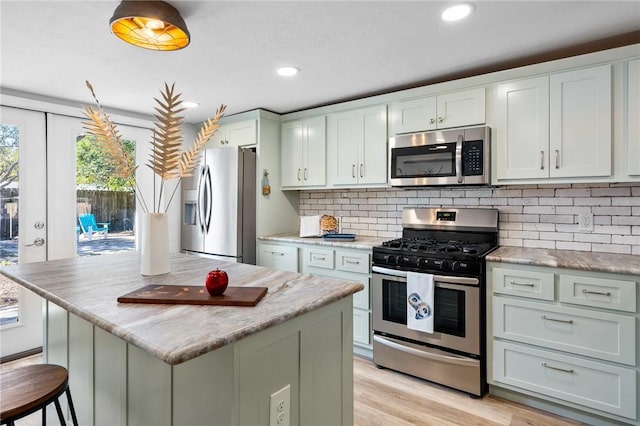 kitchen with light wood finished floors, backsplash, a kitchen island, recessed lighting, and stainless steel appliances