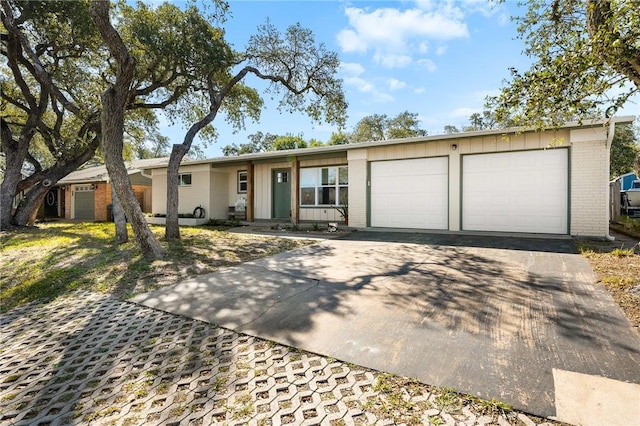 single story home with board and batten siding, a garage, brick siding, and driveway