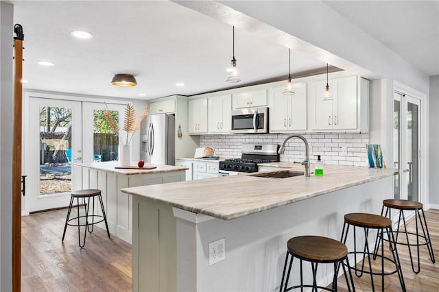 kitchen with light wood-style flooring, french doors, appliances with stainless steel finishes, and a sink