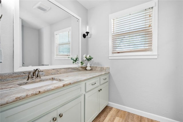 bathroom featuring visible vents, vanity, baseboards, and wood finished floors