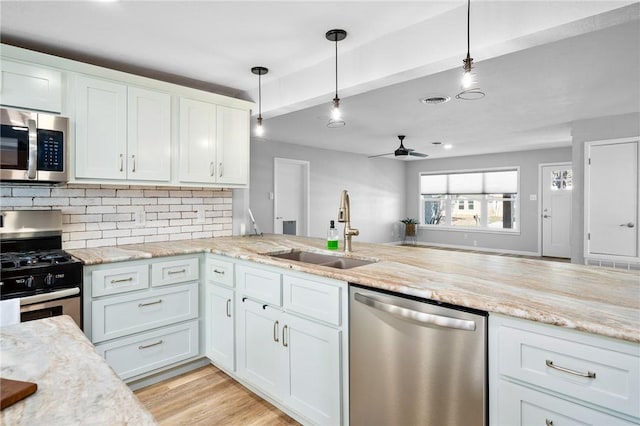 kitchen with visible vents, light wood-style flooring, a sink, tasteful backsplash, and stainless steel appliances