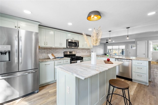 kitchen with light wood finished floors, a peninsula, stainless steel appliances, and a center island