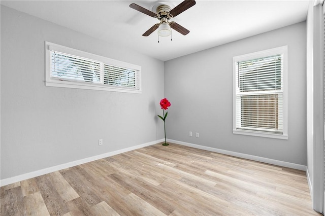 spare room featuring a ceiling fan, light wood-type flooring, and baseboards