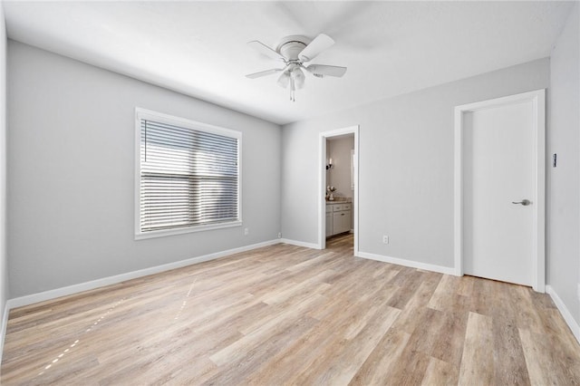 unfurnished bedroom featuring ensuite bathroom, a ceiling fan, baseboards, and light wood finished floors