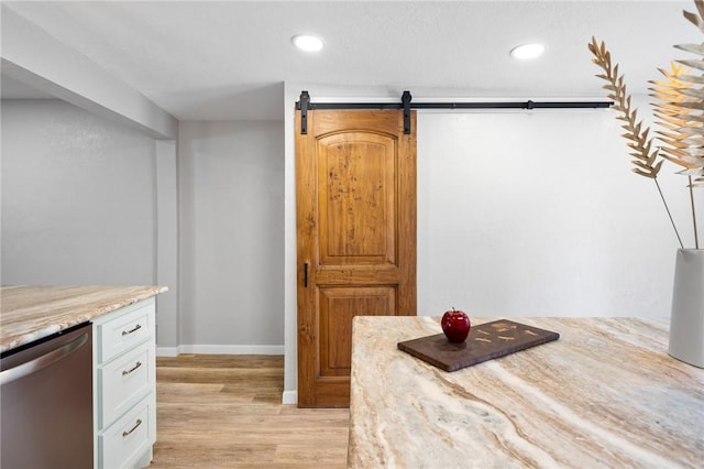 kitchen with stainless steel dishwasher, a barn door, recessed lighting, and light wood finished floors