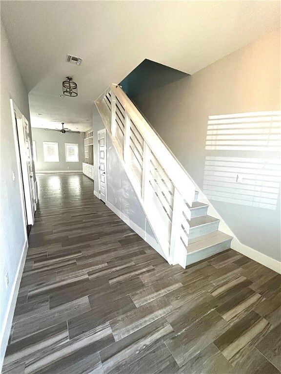 stairs with wood-type flooring and ceiling fan