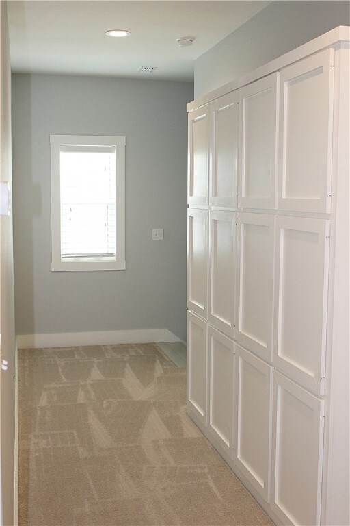 hall with light colored carpet