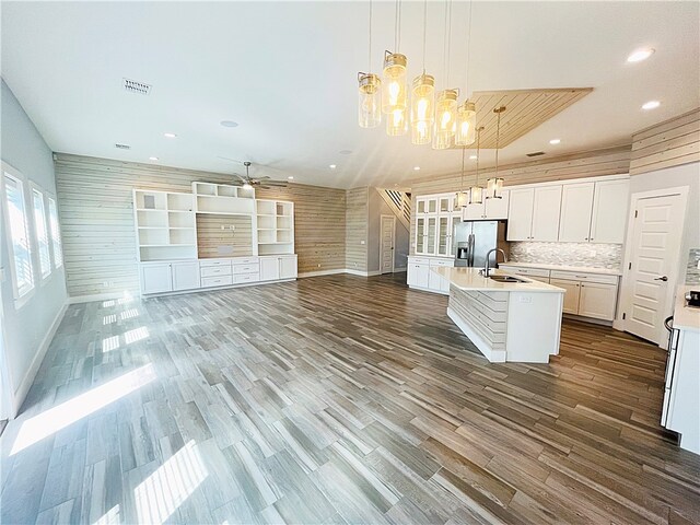 kitchen with wood-type flooring, stainless steel fridge with ice dispenser, pendant lighting, sink, and a kitchen island with sink