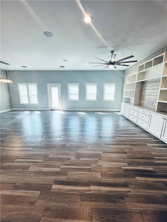 unfurnished living room with ceiling fan and dark hardwood / wood-style flooring