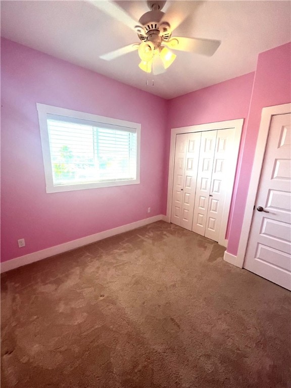 unfurnished bedroom featuring ceiling fan, a closet, and dark carpet