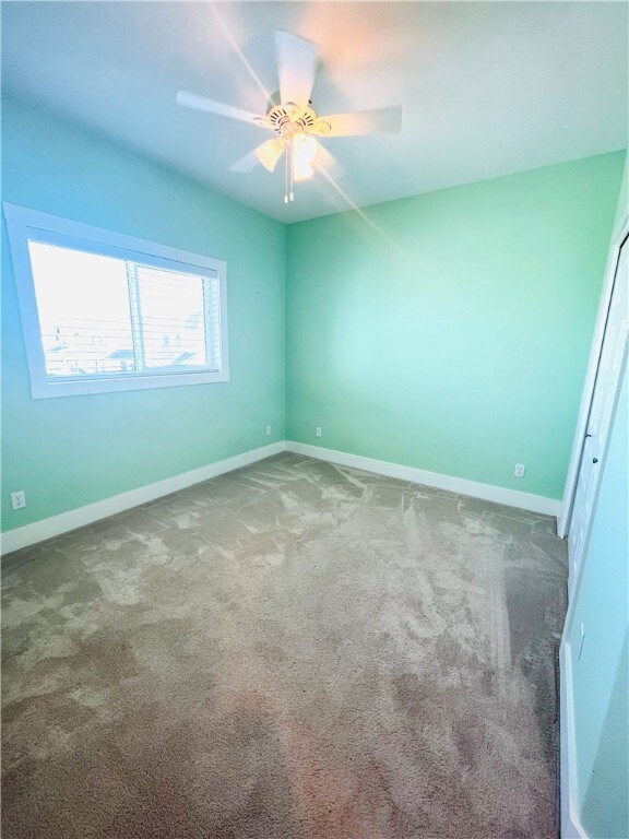 carpeted spare room with ceiling fan