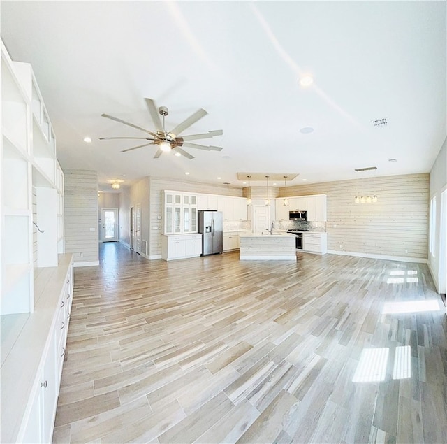 unfurnished living room featuring ceiling fan and light hardwood / wood-style floors