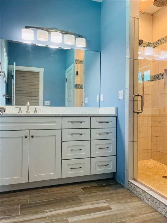 bathroom featuring hardwood / wood-style flooring, vanity, and walk in shower