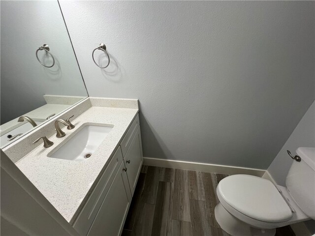 bathroom with toilet, vanity, and hardwood / wood-style floors