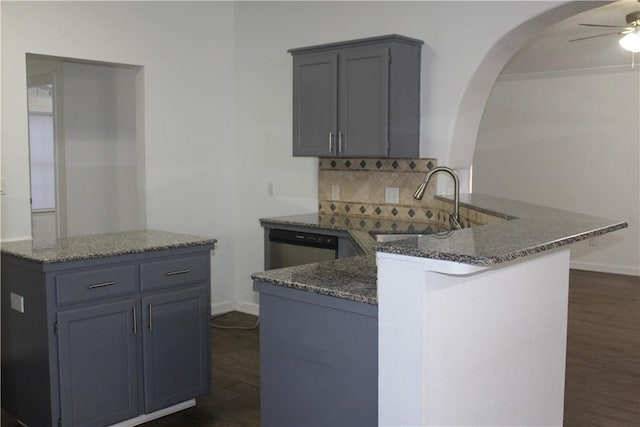 kitchen with sink, dark stone countertops, backsplash, dark hardwood / wood-style flooring, and kitchen peninsula