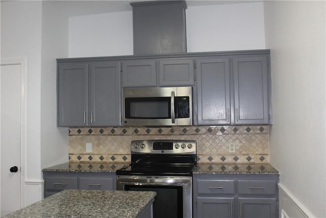 kitchen featuring gray cabinets, appliances with stainless steel finishes, and dark stone counters