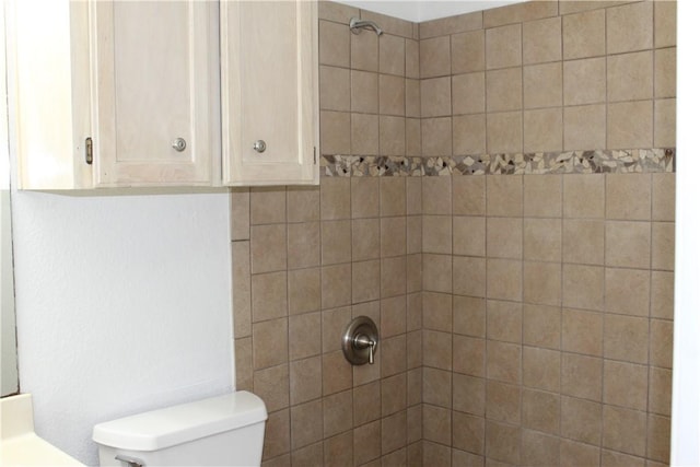 bathroom featuring a tile shower and toilet