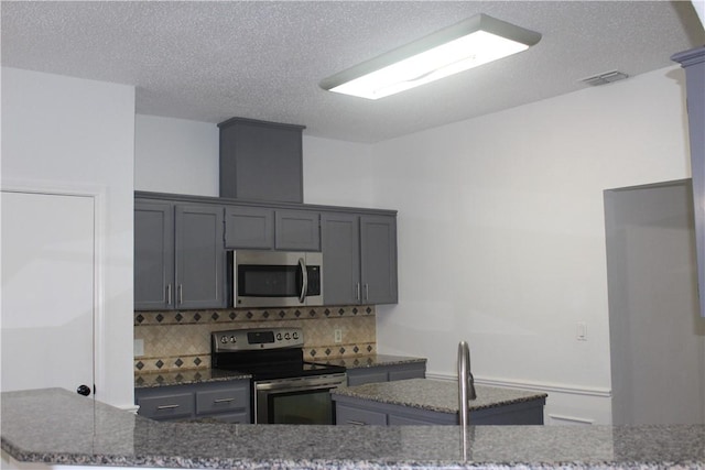 kitchen featuring tasteful backsplash, appliances with stainless steel finishes, gray cabinets, and a textured ceiling