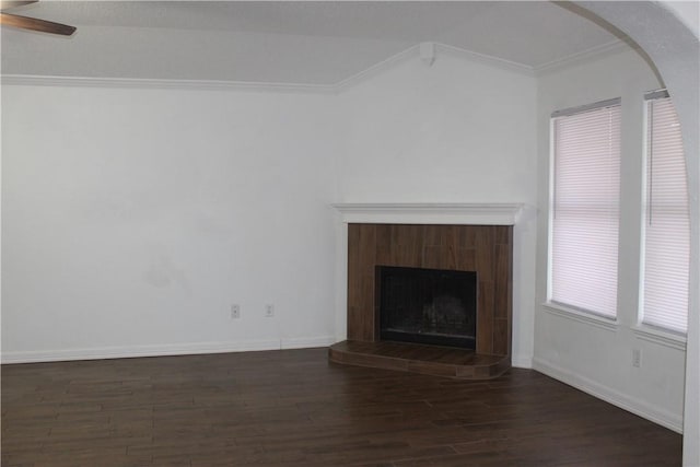 unfurnished living room featuring ceiling fan, ornamental molding, dark hardwood / wood-style floors, and a tiled fireplace